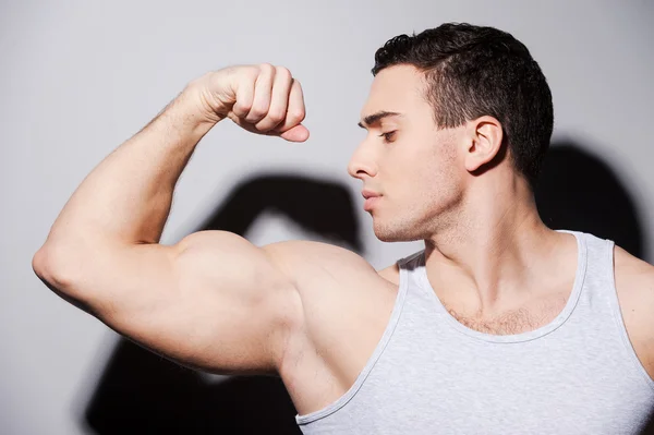 Uomo muscolare mostrando il suo bicipite — Foto Stock