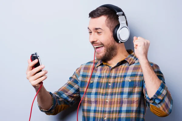 Mann mit Kopfhörer hält Handy in der Hand — Stockfoto