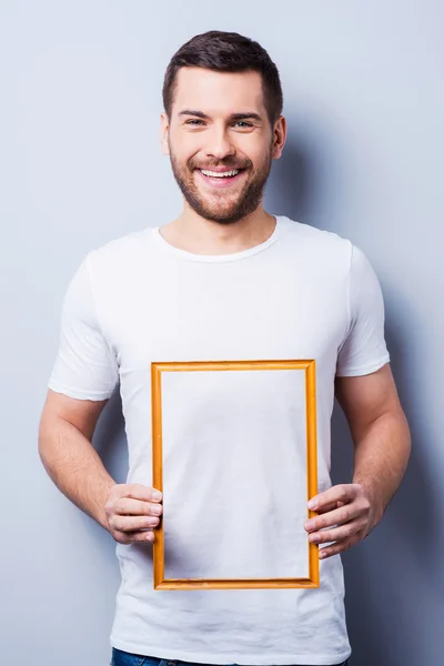 Man in T-shirt holding a picture frame — Stock Photo, Image