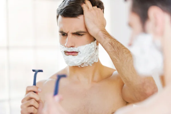 Hombre con crema de afeitar celebración de afeitar —  Fotos de Stock