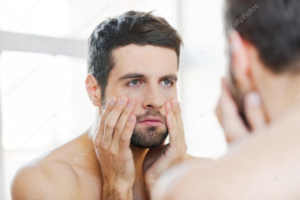 Frustrated man standing against mirror