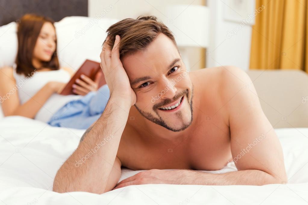 Shirtless man lying in bed