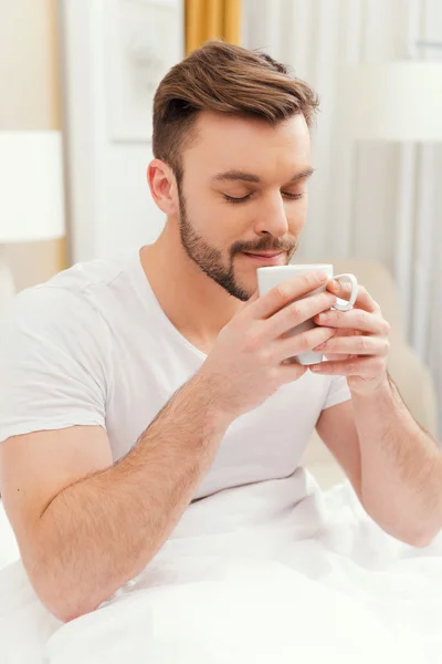 Man holding cup in bed — Stock Photo, Image