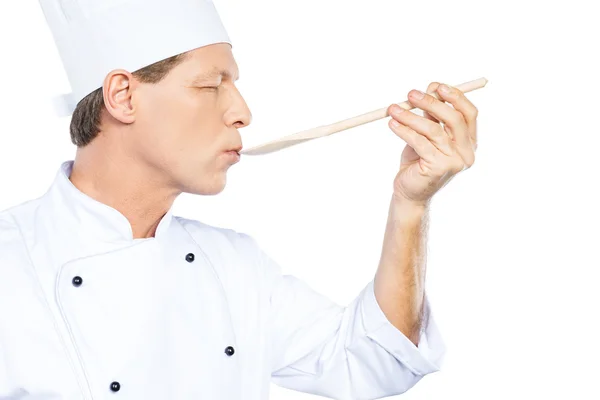 Chef eating from wooden spoon — Stock Photo, Image