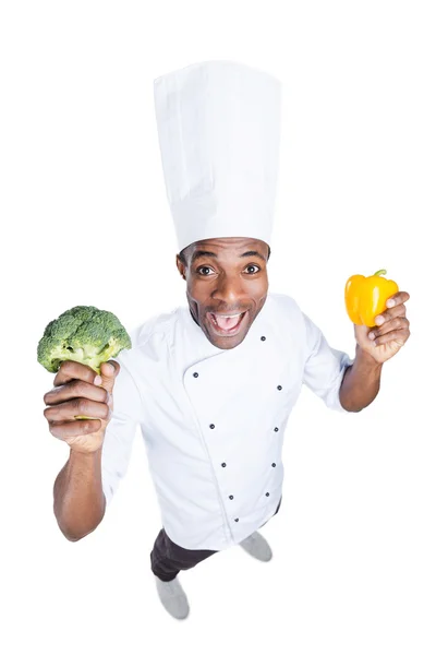 Chef africano estirando brócoli y pimienta —  Fotos de Stock