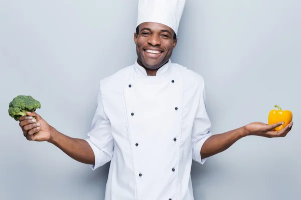 African chef holding pepper  and broccoli — Stock Photo, Image