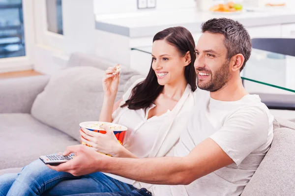 Loving couple eating popcorn and watching TV