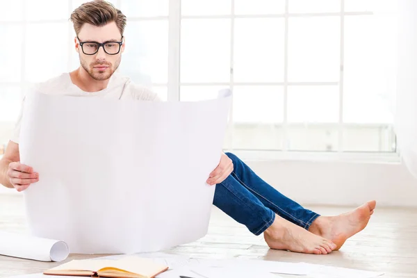 Thoughtful young man examining blueprint — Stock Photo, Image