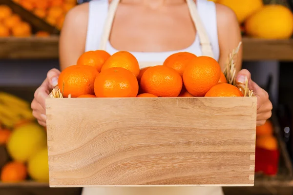 Frau hält Holzbehälter mit Mandarinen — Stockfoto