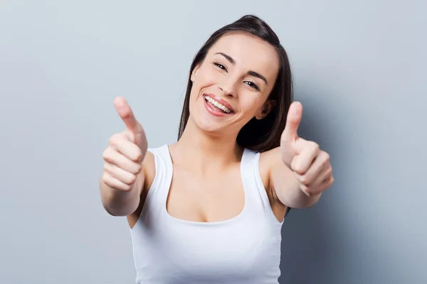 Vrouw gebaren op camera en glimlachen — Stockfoto