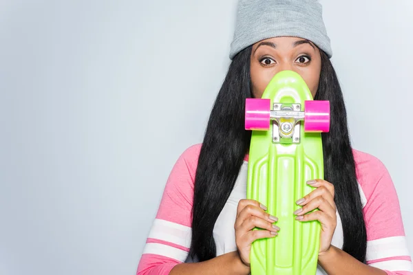 African woman hiding behind skateboard — Stock Photo, Image