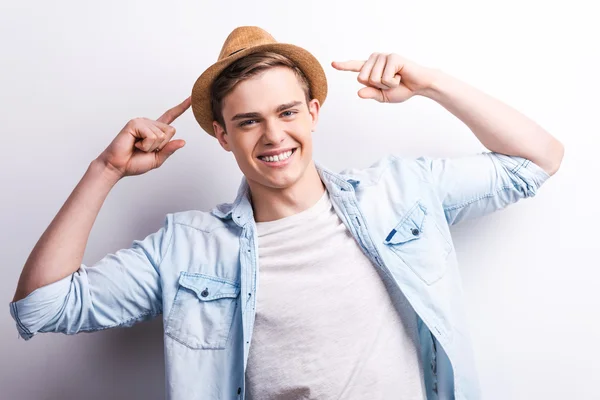 Jeune homme souriant et pointant sur le chapeau — Photo