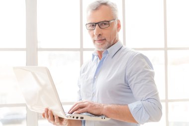 Dizüstü bilgisayarda çalışan kıdemli adam.