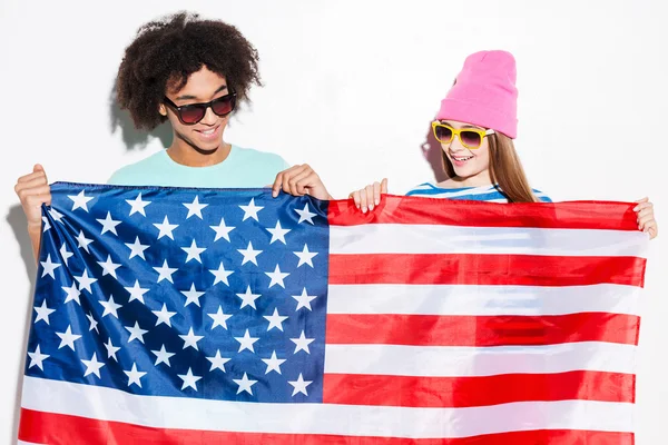 Pareja joven sosteniendo bandera americana — Foto de Stock