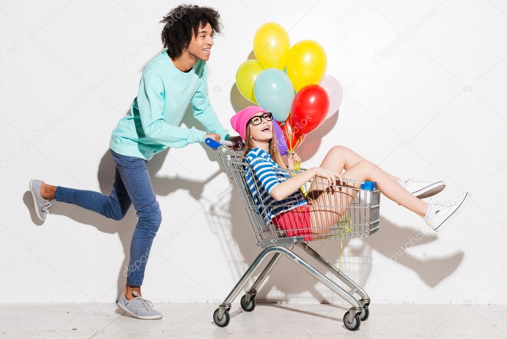 Boy carrying his girlfriend in shopping cart