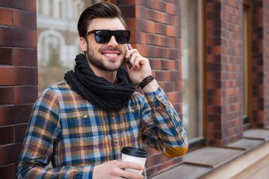 Kahve ve cep telefonu tutan adam