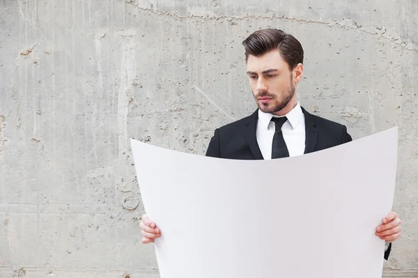 Young businessman examining blueprint — Stock Photo, Image