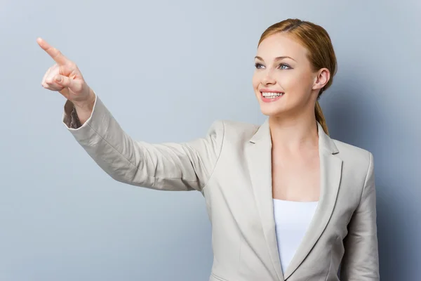 Souriant jeune femme d'affaires pointant du doigt — Photo