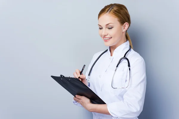 Confident female doctor writing in clipboard — Stock Photo, Image