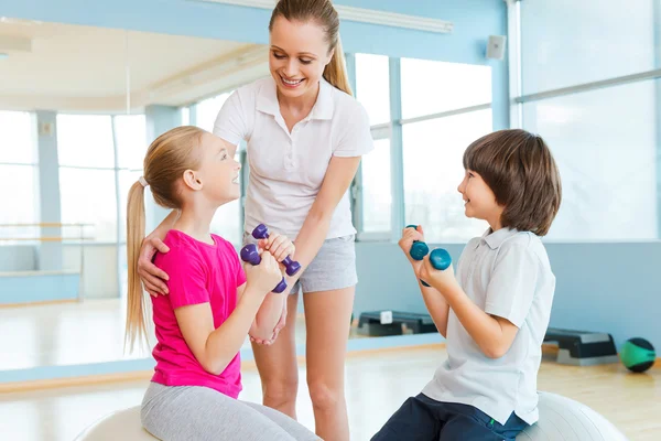 Instructor que ayuda a los niños a hacer ejercicio — Foto de Stock
