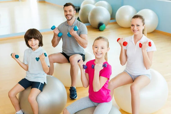 Feliz família desportiva exercitando com halteres — Fotografia de Stock