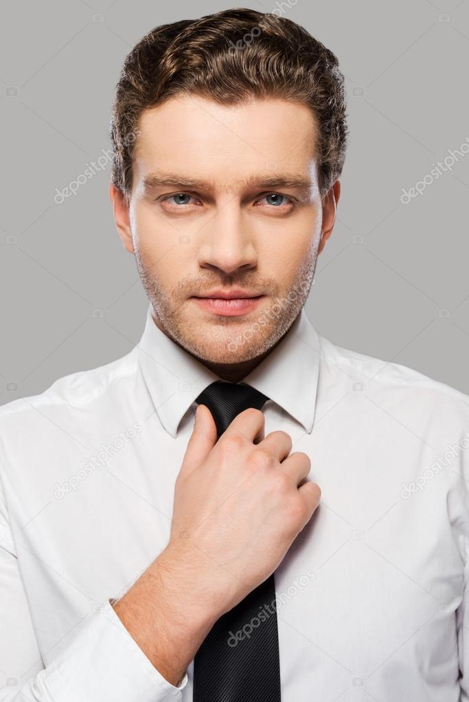 Man in shirt and tie adjusting  necktie
