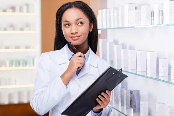Mujer de pie cerca de un estante en la farmacia — Foto de Stock