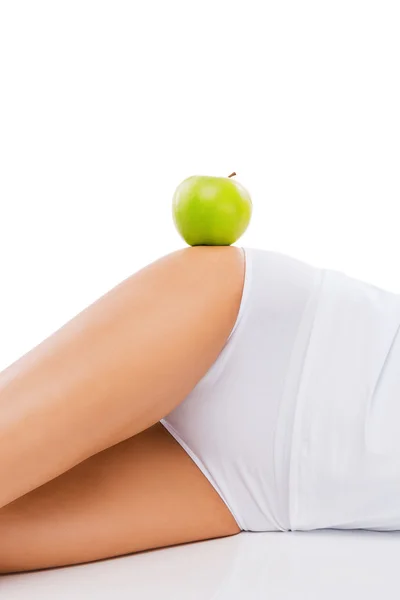 Mujer acostada con manzana en la cadera — Foto de Stock