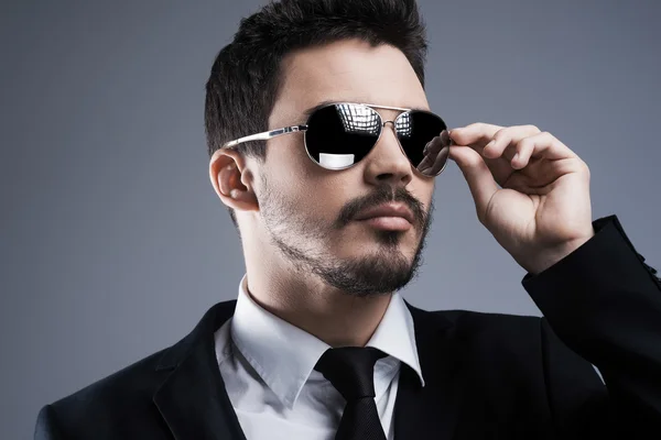 Hombre en ropa formal ajustando sus gafas de sol — Foto de Stock