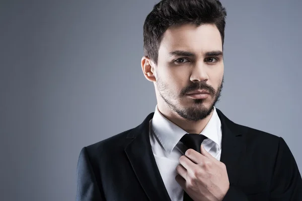Mies muodollisissa vaatteissa säätämässä solmiota — kuvapankkivalokuva