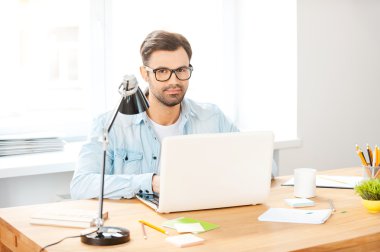 Gömlek ve gözlük dizüstü bilgisayarda çalışan adam