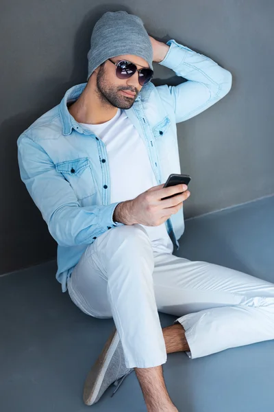Człowiek w okulary trzymając telefon komórkowy — Zdjęcie stockowe