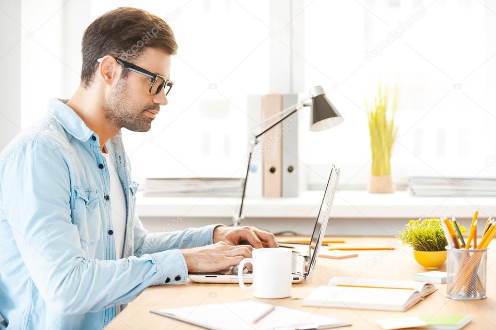 Man in shirt and eyewear working on laptop
