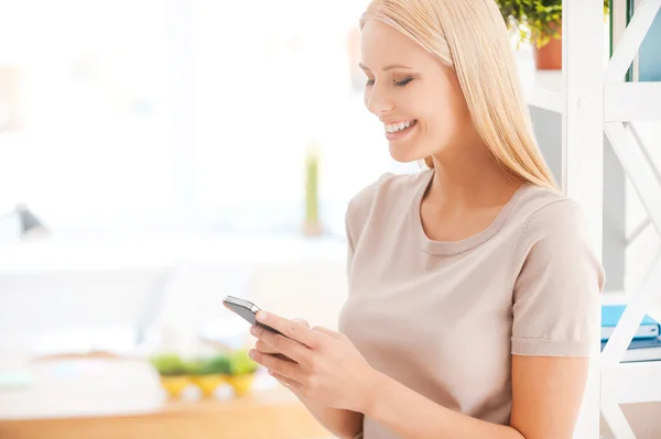 Woman holding mobile phone in office — Stock Photo, Image