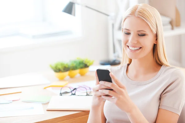 Woman holding mobile phone in office — Stock Photo, Image