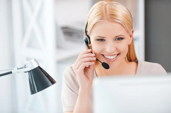 Mujer trabajando en la computadora y ajustando auriculares — Foto de Stock