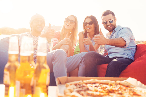 People showing thumbs with pizza and beer