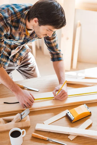 Carpenter making measurements on the wooden plank — Stock Photo, Image