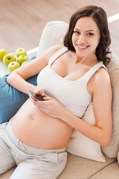 Zwangere vrouw bedrijf mobiele telefoon — Stockfoto