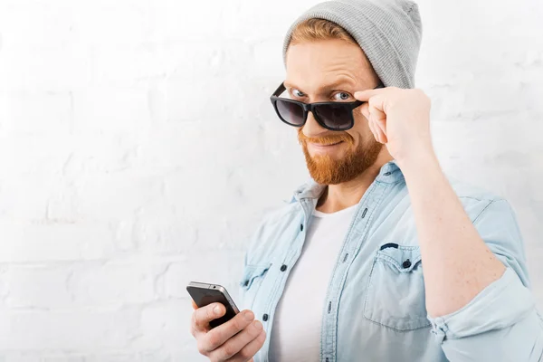 Бородатый мужчина держит мобильный телефон — стоковое фото