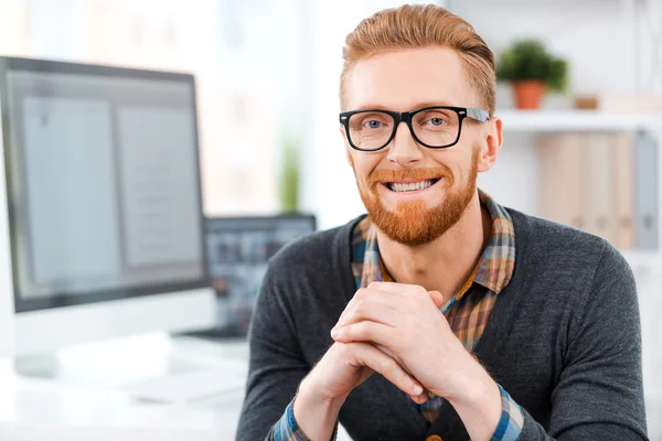 Бородатий чоловік в окулярах сидить на робочому місці — стокове фото