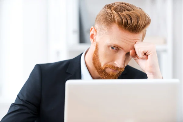 Frustrado hombre de negocios barbudo trabajando en el ordenador portátil —  Fotos de Stock