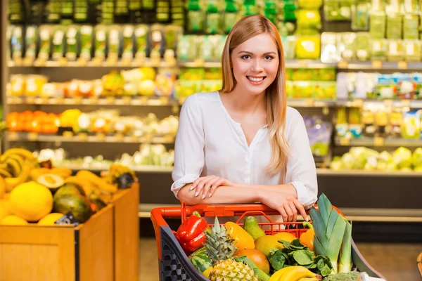 Kvinnan lutar sig på kundvagn i butik — Stockfoto