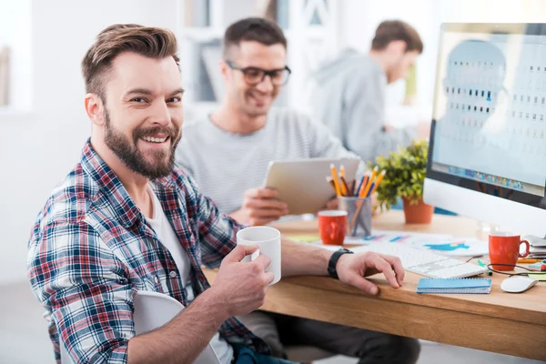 Man holding a cup of coffee with his colleagues