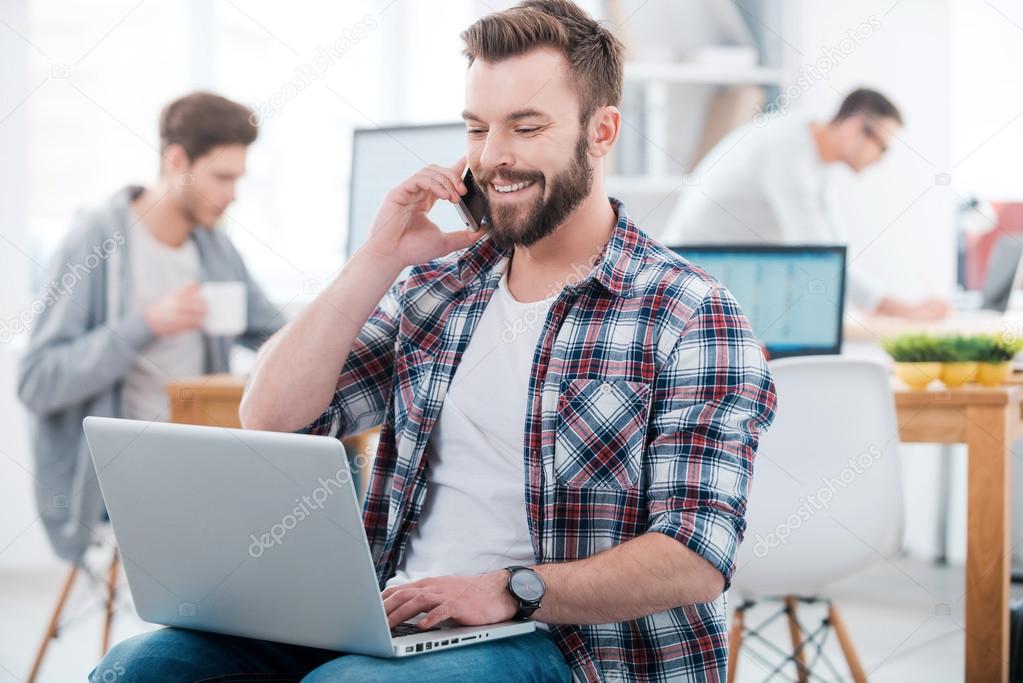 Man working on laptop and talking on phone