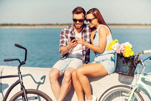 Пара смотрит на мобильный телефон рядом с велосипедами — стоковое фото