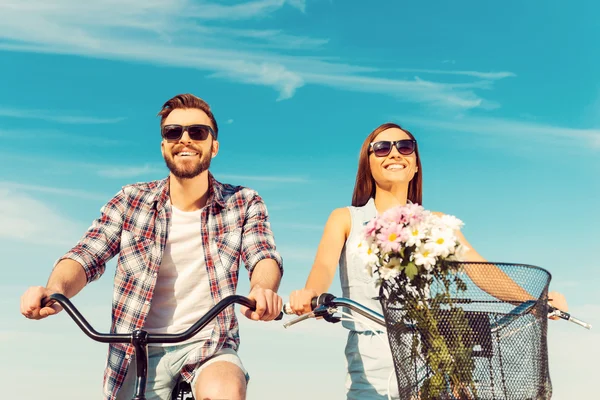 Jovem casal sorrindo e andando de bicicleta — Fotografia de Stock