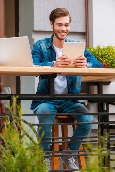 Человек держит цифровой планшет на тротуаре кафе — стоковое фото