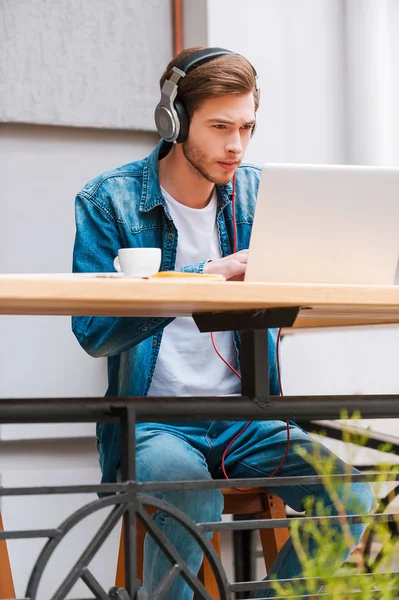 Homem em fones de ouvido trabalhando no laptop — Fotografia de Stock