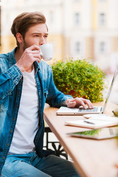 Człowiek pije kawę i pracy na laptopie — Zdjęcie stockowe